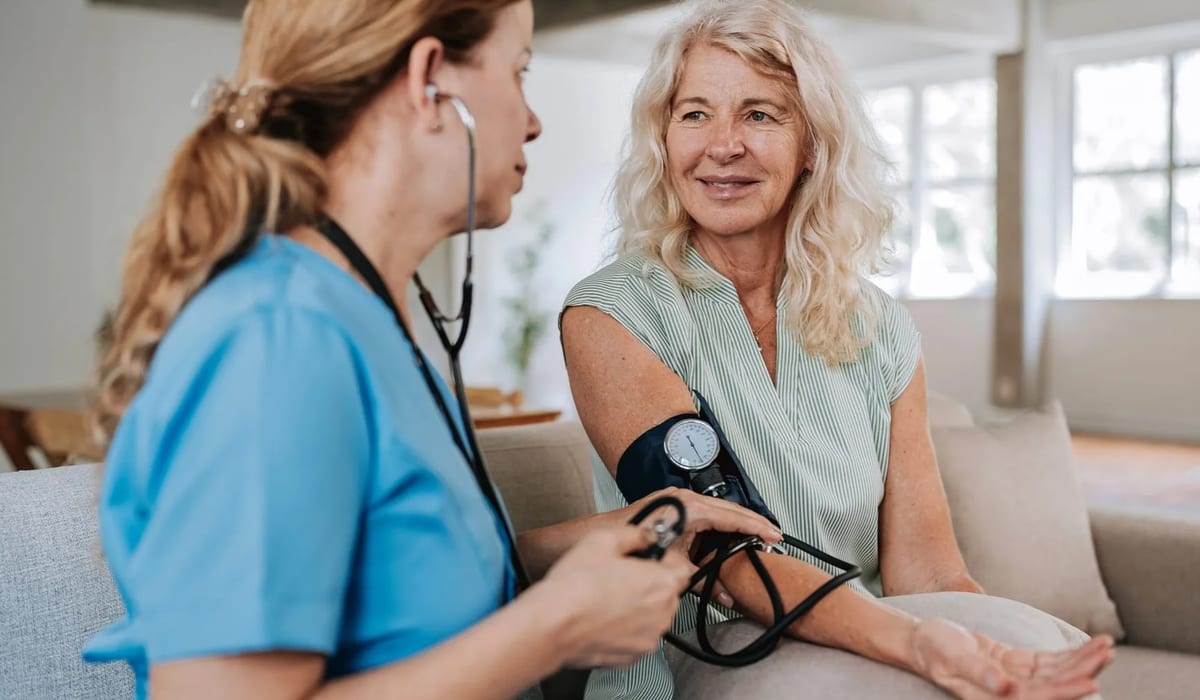 Licensed nurse checking blood pressure of elderly patient during home visit